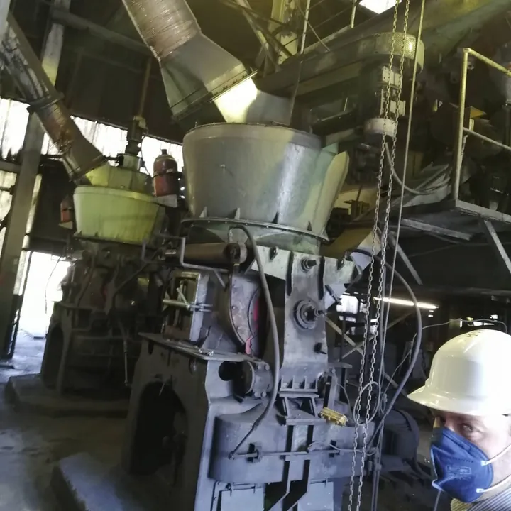 Heavy industrial mills, with Guy Entract in a hard hat and mask in the corner of the frame